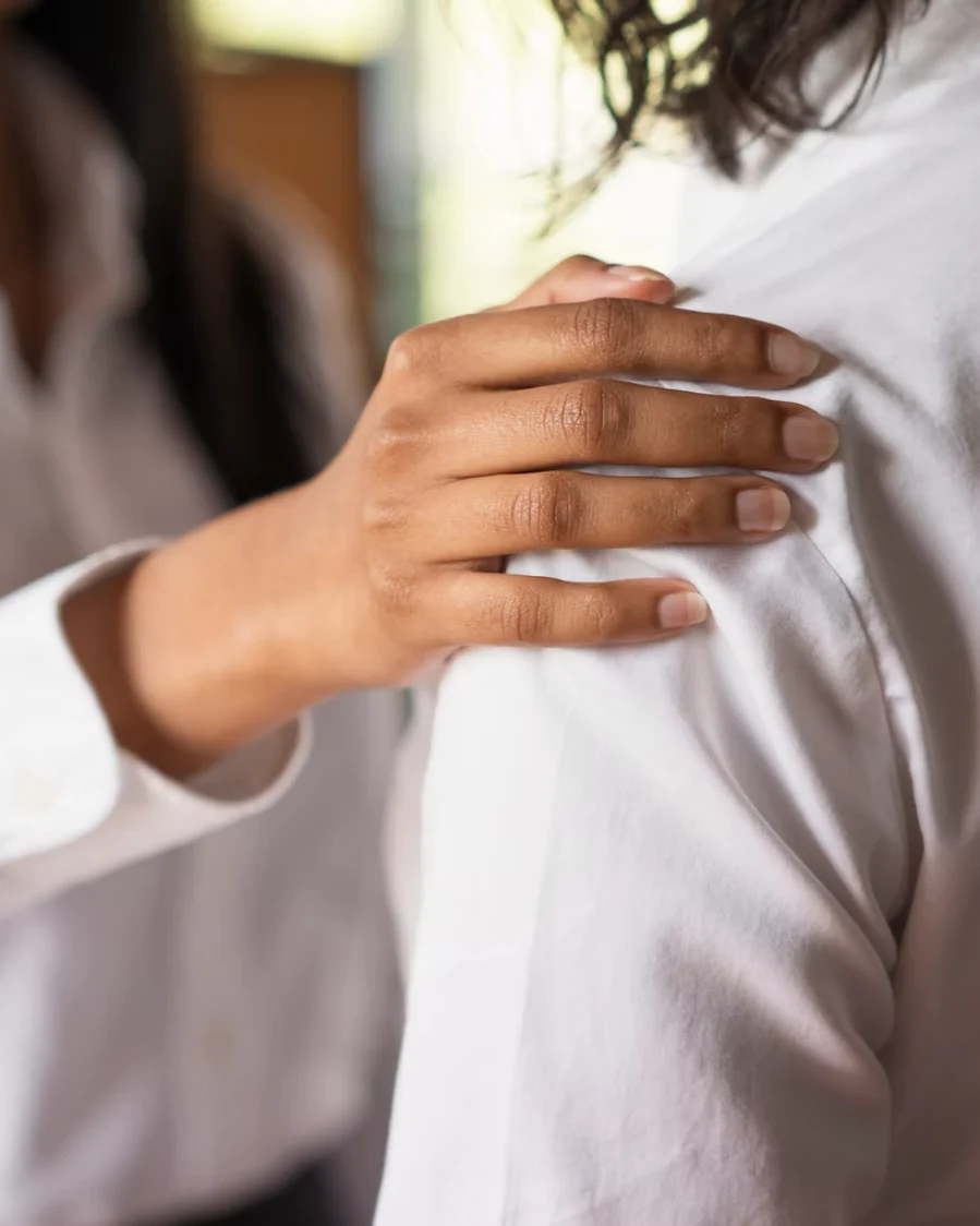 A hand resting on a patient's shoulder during an unhurried consultation